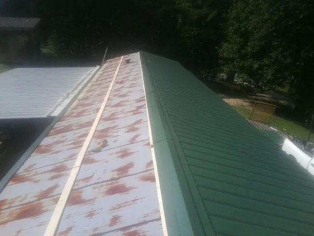 Old rusted panels beside newly installed green metal roofing — Wind Damage Roof Repair by Roofing Brothers in O Fallon