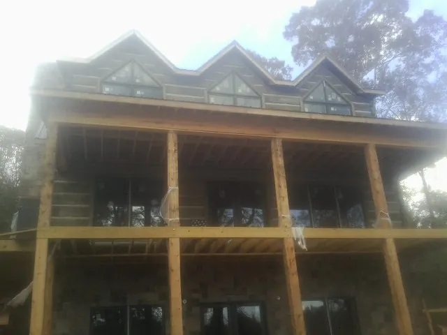 Dormers and porch framing on a large log home under construction — Roof Coating work by our crew in O Fallon