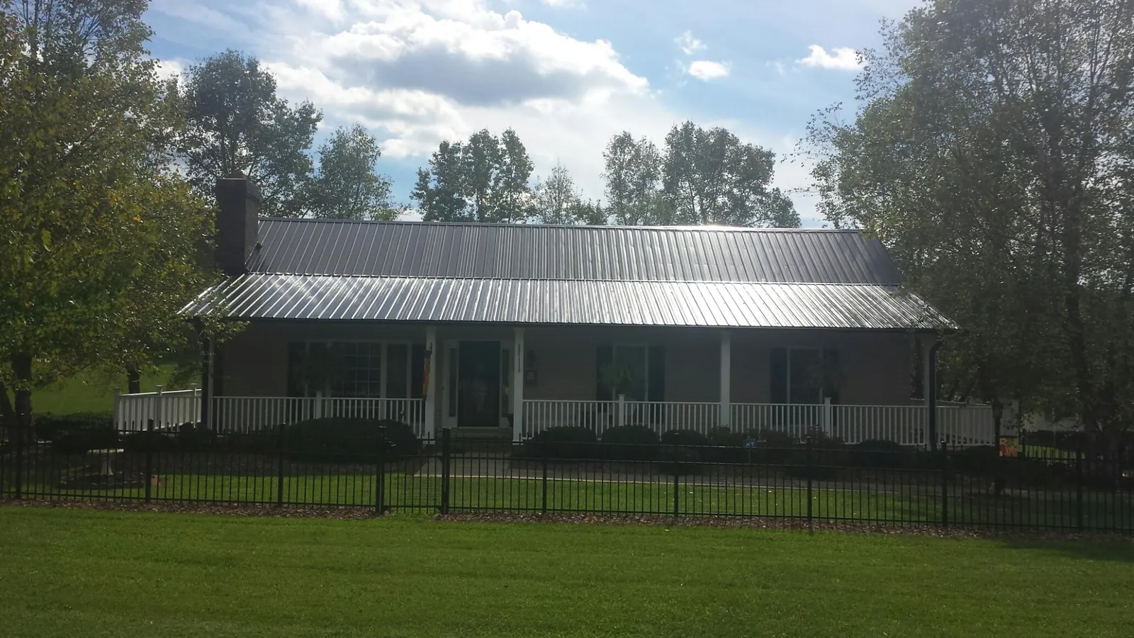 Gray metal roof on a brick ranch with a full width front porch — Gutter Guard Installation work by our crew in O Fallon